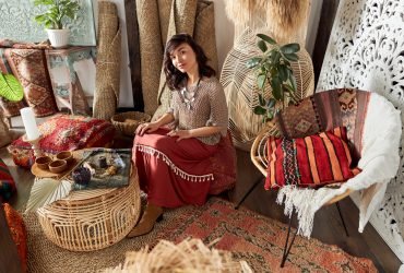 Mature beautiful dark haired woman in shamanic ethnic outfit in bali style decorated room is doing rappa ceremony